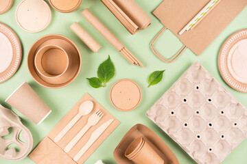 Flat lay with eco tableware, paper utensils and wooden bamboo cutlery set over light green...