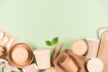 Eco paper utensils and wooden bamboo cutlery set, food containers and paper cups over light green...