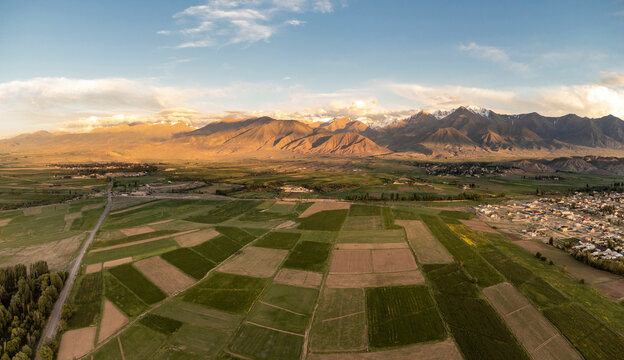 Aerial panorama of mountains and farmland in rural Kyrgyzstan.