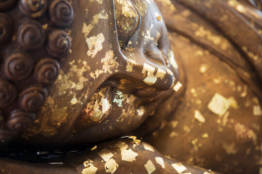 Closeup of the face of buddha's image covering with gold leaf.