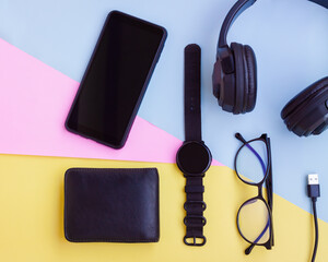 Smartphone,Smartwatch,Black Headphone,Black Wallet,USB cable and Eyeglasses on pink,blue and yellow...