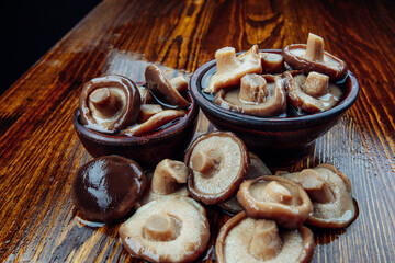 Mushrooms in clay cups and scattered on a wooden table . Healthy village food .