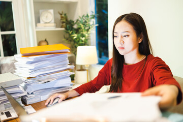 Freelancer woman working overtime at home office and doing paperwork and accounting