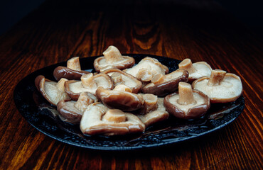 A plate of pickled mushrooms . Healthy village food . Pickled black milk mushroom .