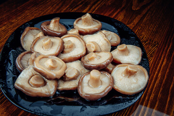 Beautiful pickled mushrooms in a black glass plate . Healthy village food . Pickled black milk mushroom .