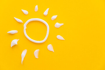 Top view of sun sign from sunscreen on yellow background.