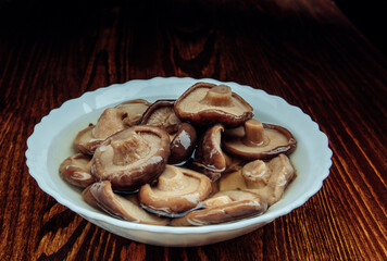 A plate of pickled mushrooms . Healthy village food . Pickled black milk mushroom .