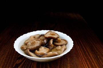 A plate of pickled mushrooms . Healthy village food . Pickled black milk mushroom .