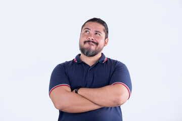 A confident man in a blue polo shirt looking up with his arms crossed. A bearded guy in his late 30s and mixed ethnicity.