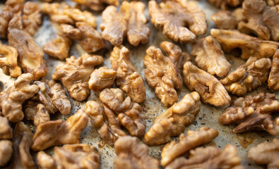 Roasted walnut lies on a metal baking sheet. Protein, healthy nuts, shortage of walnuts, more expensive snacks.