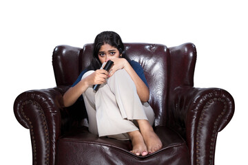 Asian woman holding a television remote sitting on the couch with a scared expression