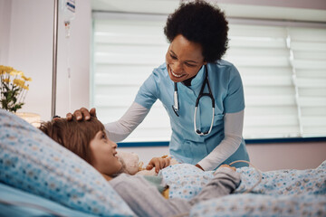 Caring black nurse talks to small boy at intensive care unit at the hospital.