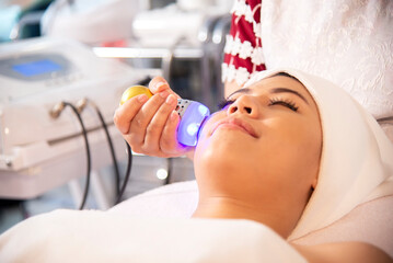 Asian woman getting lifting anti-aging, face massage and skincare by electroporation facial therapy...