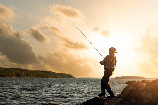 bank fishing. fisherman with spinning rod at sunset. copy space