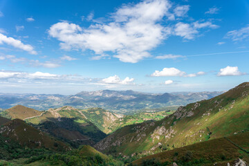 mountain landscape full of vegetation with a slightly cloudy blue sky