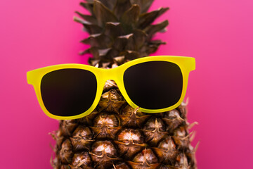 Top view of sunglasses on pineapple isolated on pink.
