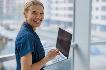 Smiling female healthcare worker using laptop while working at doctor's office