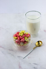 Snacks with raspberry and banana flavor in the shape of hearts and flowers. A bowl with a quick breakfast and a glass of milk on a white background