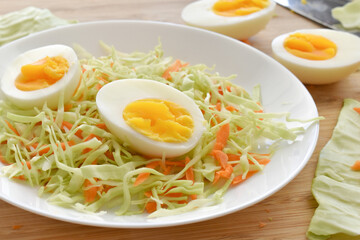 Boiled egg salad with cabbage and carrot. Coleslaw with boiled on a white plate.