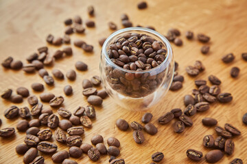 Coffee beans in a transparent bowl over a wood tablet with copy space.