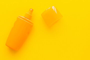 Top view of sunscreen with cup on yellow background.