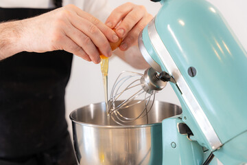 A man baker cooking a red velvet cake at home, preparing the cake by adding egg in the machine, work at home