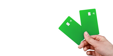 A young woman hand holds 2 green bank cards with a chip and contactless payment function in...