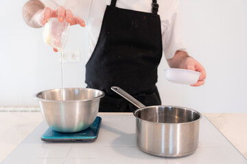 Hands of a man cooking a red velvet cake at home, preparing Swiss meringue with egg whites in a bain-marie, work at home