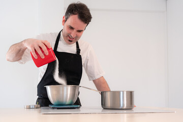 Challenger man cooking a red velvet cake at home, preparing Swiss meringue with egg whites in a...