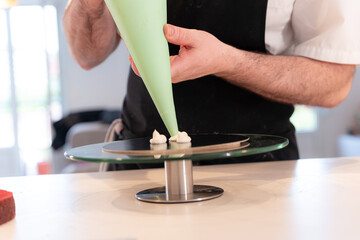 Hands of a man cooking a red velvet cake at home, assembling the triple base of the cake with the piping bag
