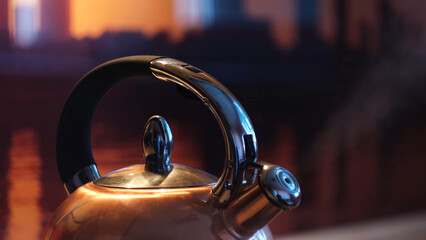 Polished kettle boiling on a gas stove in the kitchen in the evening. Concept. Close up of boiling...