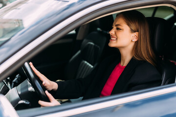 Obraz na płótnie Canvas Young woman hand pressing the horn button while driving a car through the road.