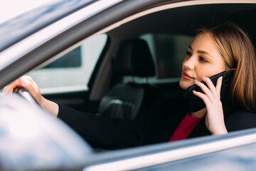 Young Businesswoman driving car and talking on cell phone concentrating on the road