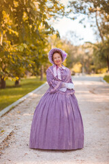 Woman in victorian dress walking in the park. Vintage fashion.