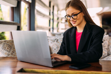 Fototapeta premium Young business woman using laptop in a cafe