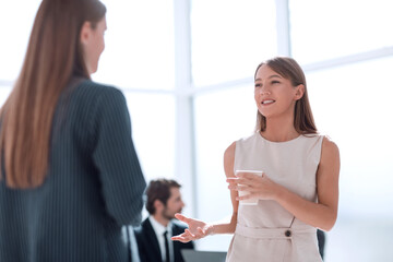 businesswoman with a glass of coffee discussing something with her colleague