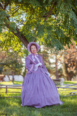 Woman in victorian dress walking in the park. Vintage fashion.