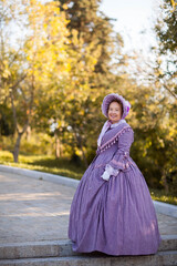 Woman in victorian dress walking in the park. Vintage fashion.