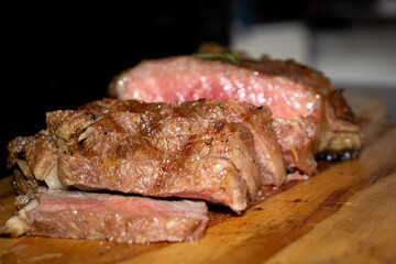 rare sirloin steak grilled, on wooden cutting board and black surface