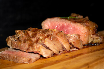 rare sirloin steak grilled, on wooden cutting board and black surface