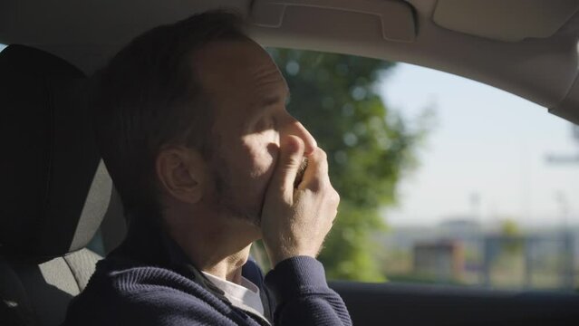 A middle-aged handsome Caucasian man thinks about something in a car - side closeup