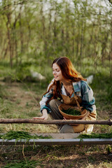 Naklejka premium Girl bird farm worker smiles and is happy pouring food into the feeder for the chickens outdoors