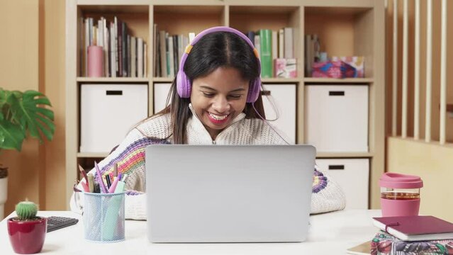 Female student using laptop in an online lesson at home. High school, college student doing her homework in a video call. 