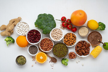 Overhead view of raw beans seeds nuts vegan food and vegetables on light surface