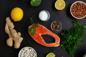 Overhead view of Raw salmon steak and vegetables on dark surface fish food