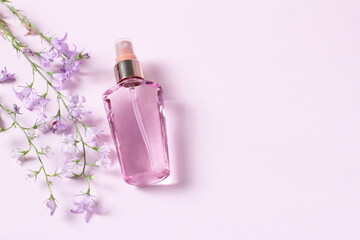 Pink perfume bottle on pink table with flowers