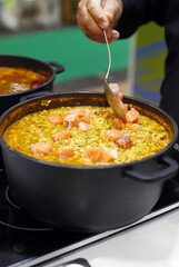 elaboración de guiso de arroz con salmón ahumado en cazuela grande al fuego