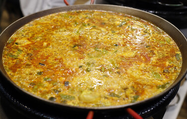 Paellera en los fogones cociendo arroz con verduras