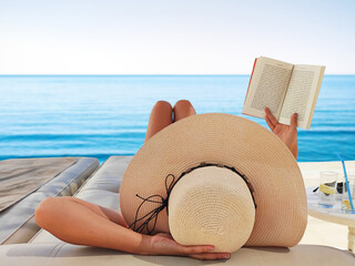 Young woman reads a book on the beach 