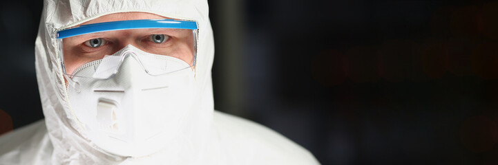 Worker in protective respirator and white coverall analyzing science experiment